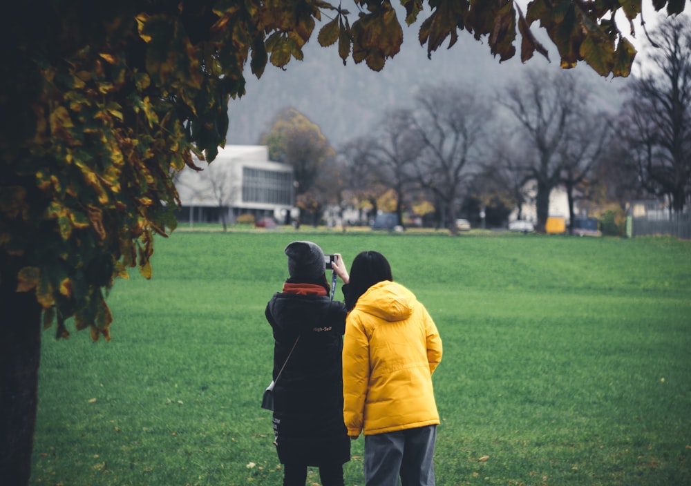 man in yellow hoodie standing on green grass field