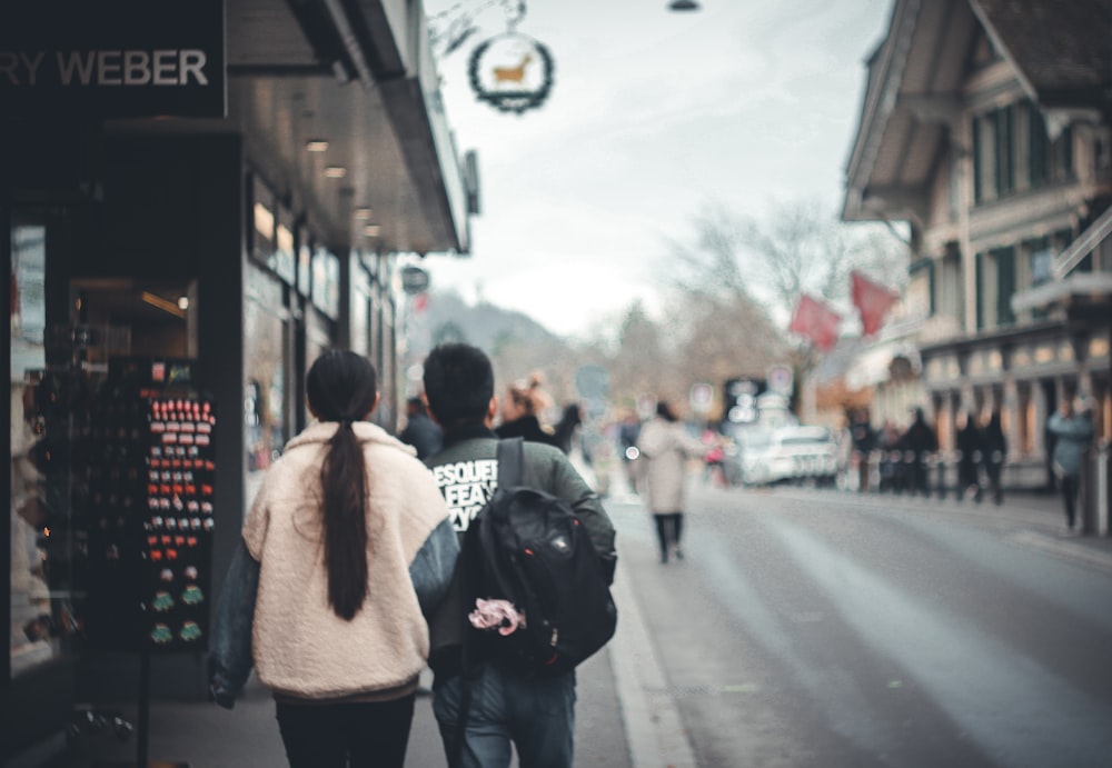 man in brown jacket and black backpack walking on sidewalk during daytime