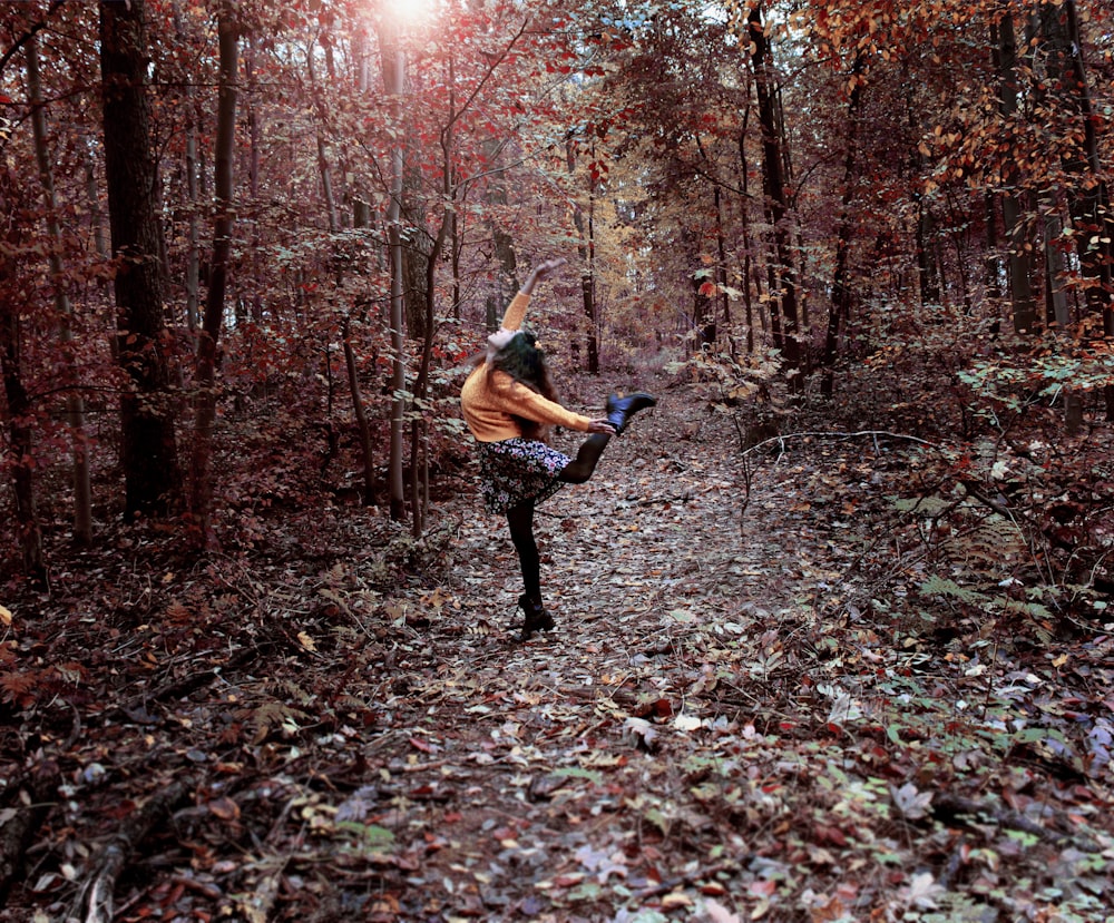 woman in brown jacket and black pants walking on forest during daytime