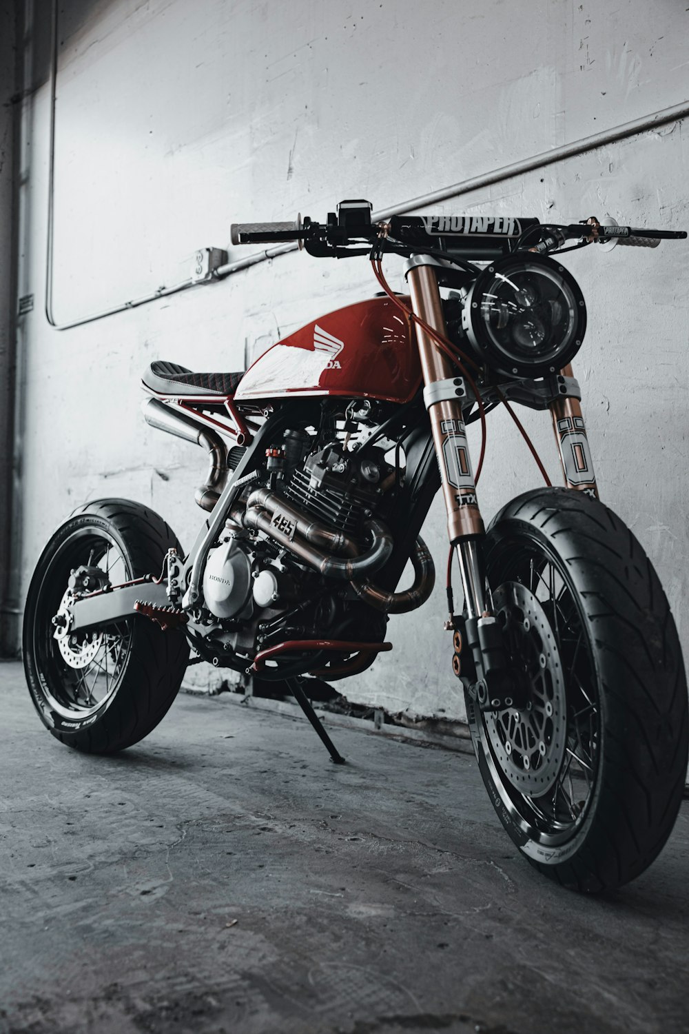 red and black motorcycle parked beside white wall