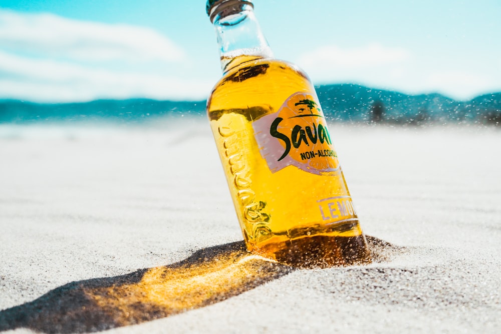 yellow and white labeled bottle on snow covered ground