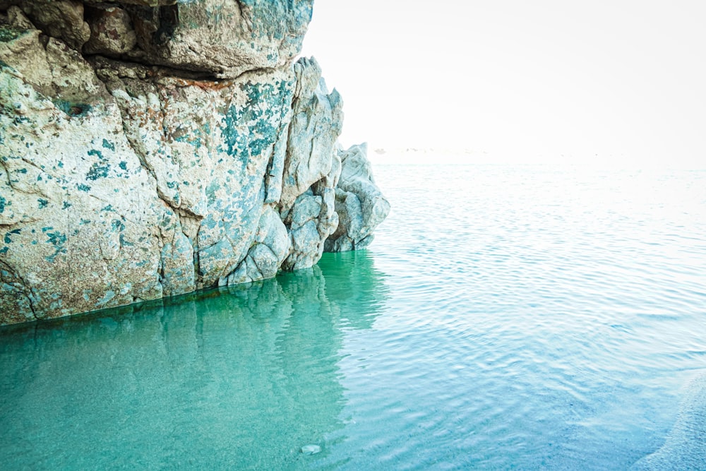 gray rocky mountain beside body of water during daytime