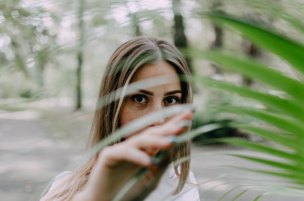 woman in white shirt covering her face with her hand