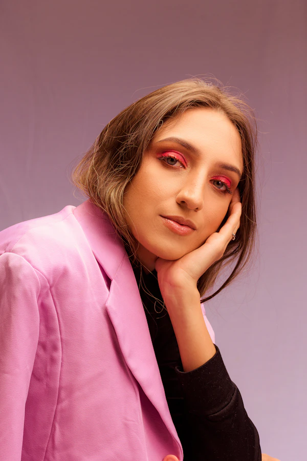 A woman in a pink blazer resting her face on her hand