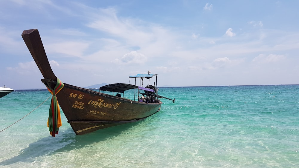 barco marrón y blanco en el mar bajo el cielo azul durante el día