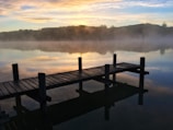 Wooden dock stretching into calm lake waters at dawn.