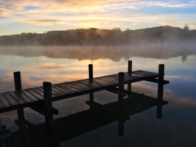 Wooden dock stretching into calm lake waters at dawn.