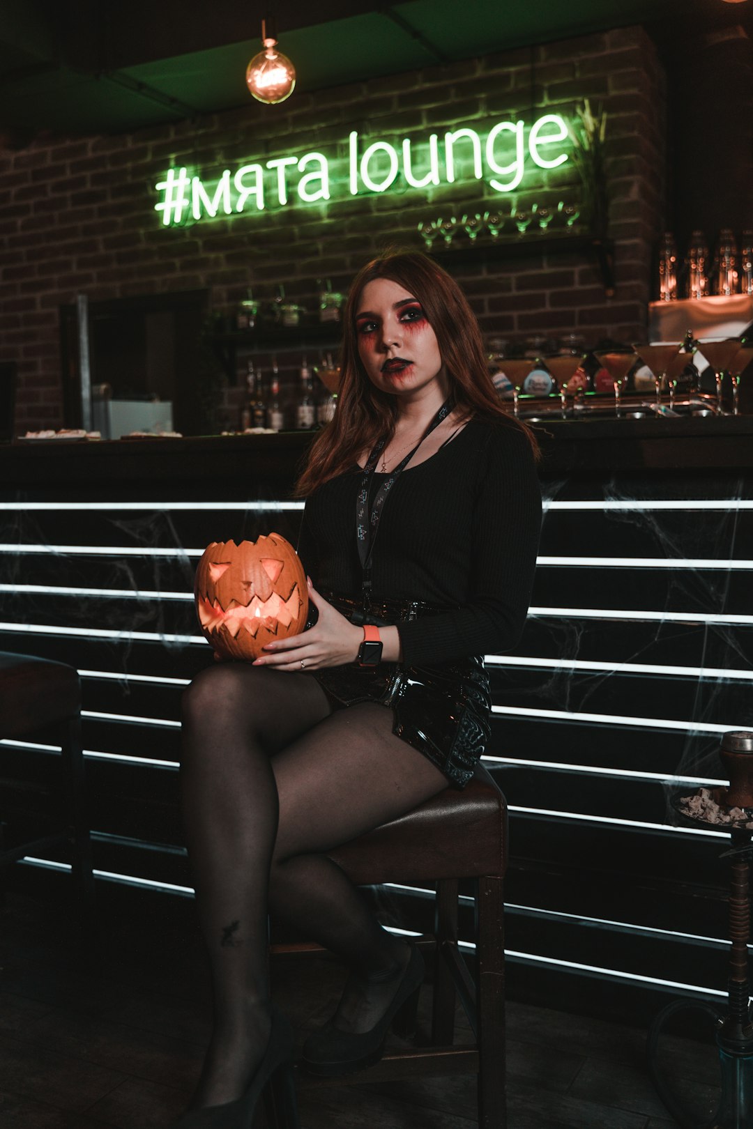 woman in black long sleeve shirt sitting on black wooden bench holding jack o lantern