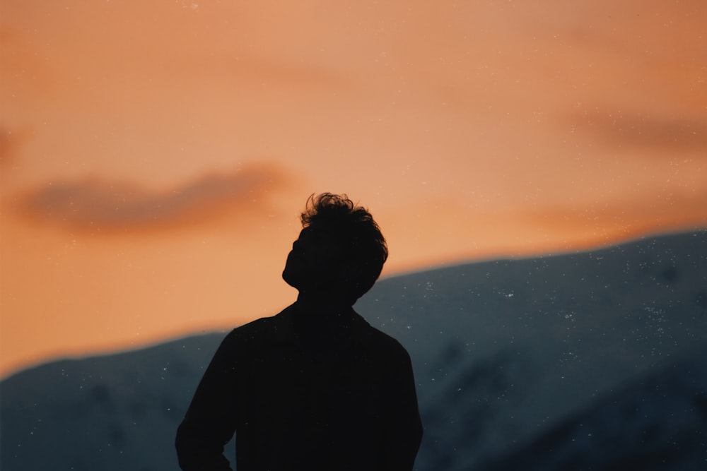 silhueta do homem de pé na montanha durante o pôr do sol