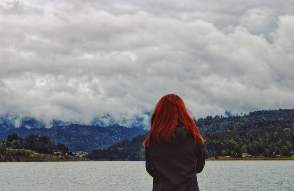 woman in black jacket standing near body of water during daytime