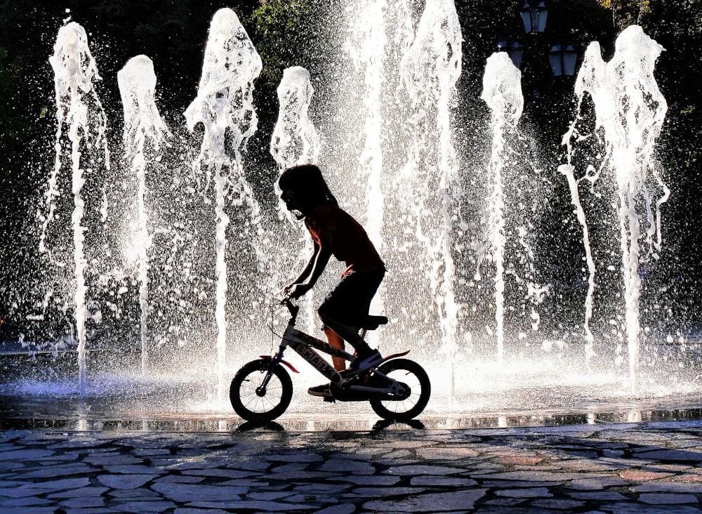 man riding bicycle on water fountain during daytime