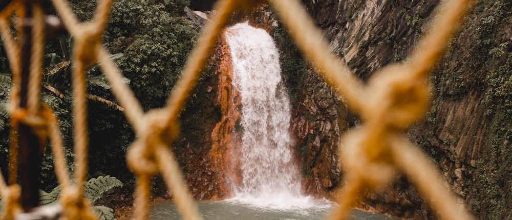 a view of a waterfall through a chain link fence