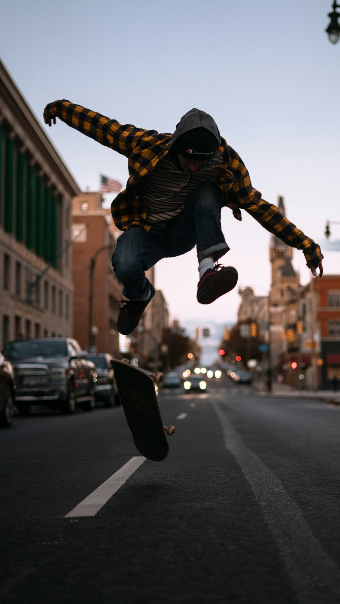 man in black and yellow jacket and black pants jumping on road during daytime