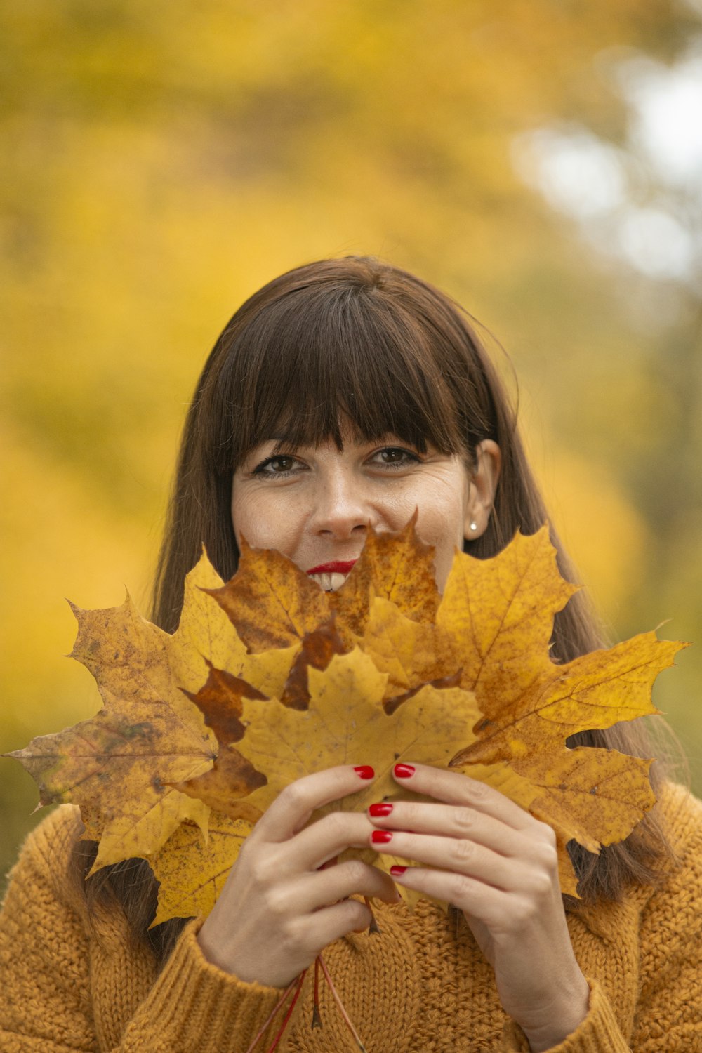 girl holding brown maple leaf