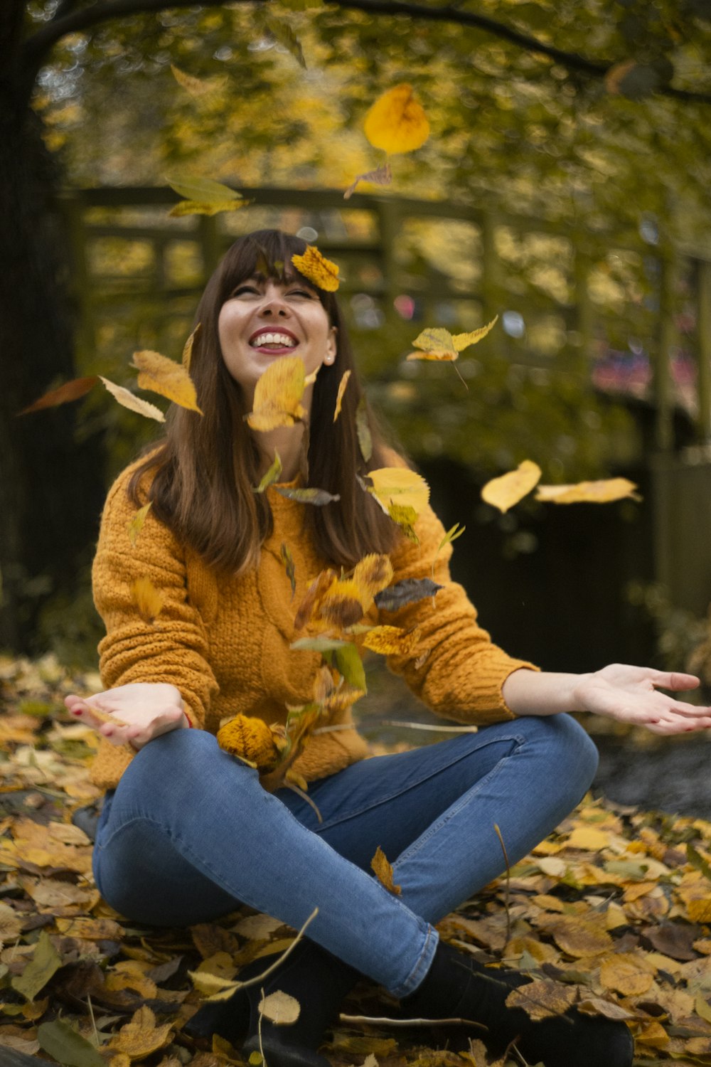 woman in brown sweater and blue denim jeans sitting on ground