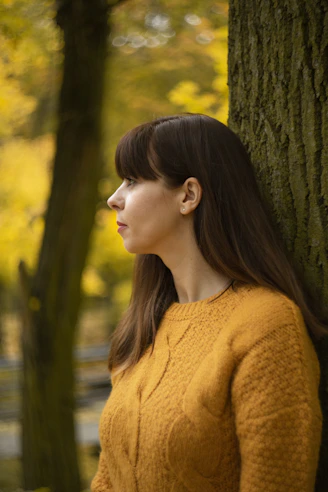 Woman wearing a cozy brown knit sweater in an autumn forest setting