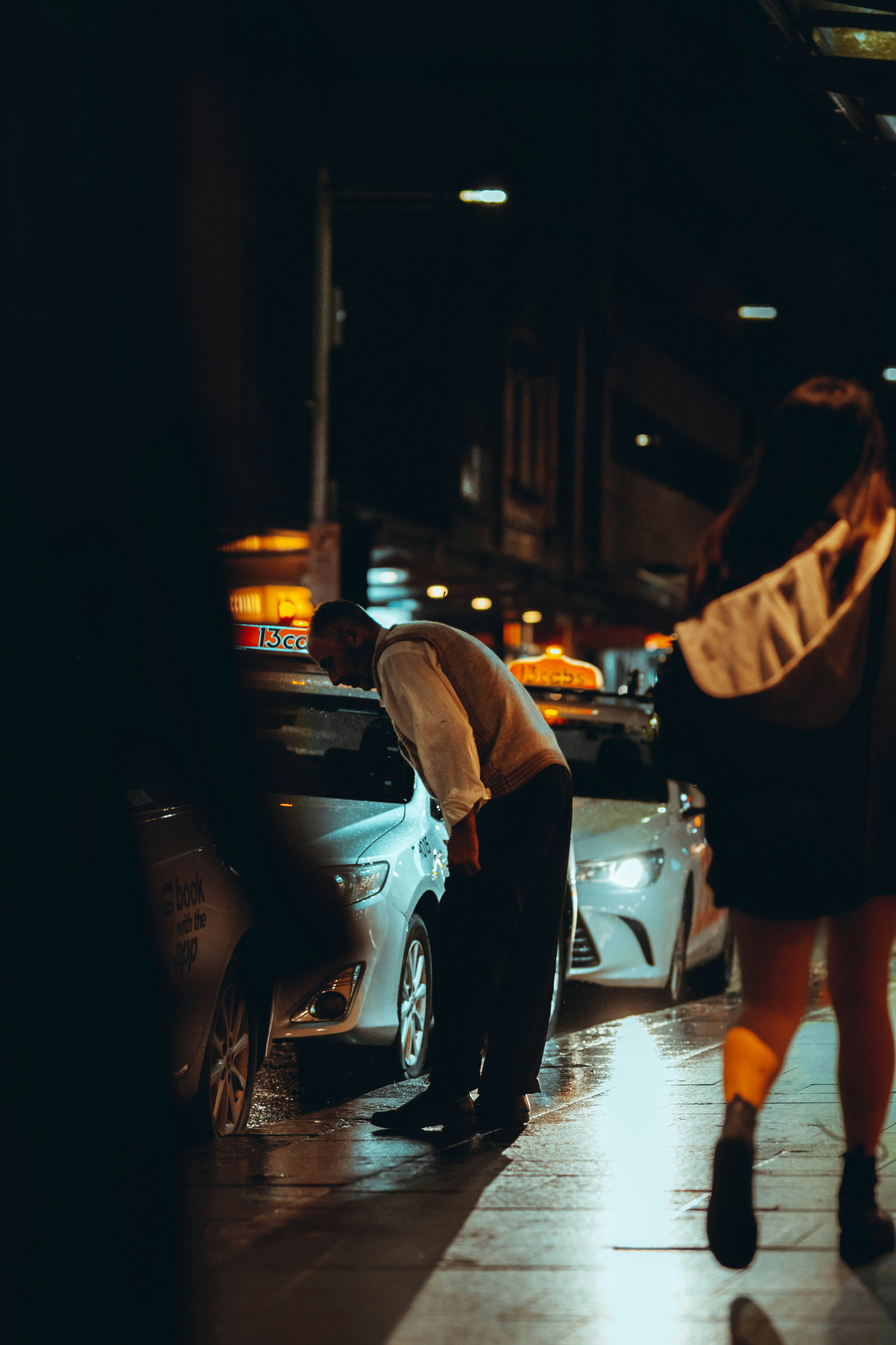 woman in black dress standing beside white car during night time