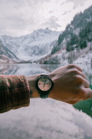 An outdoor scene featuring a person wearing a military watch while hiking in the mountains.