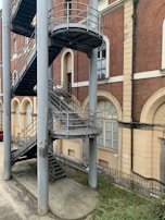 Outdoor metal spiral staircase attached to a brick building, blending style and function.