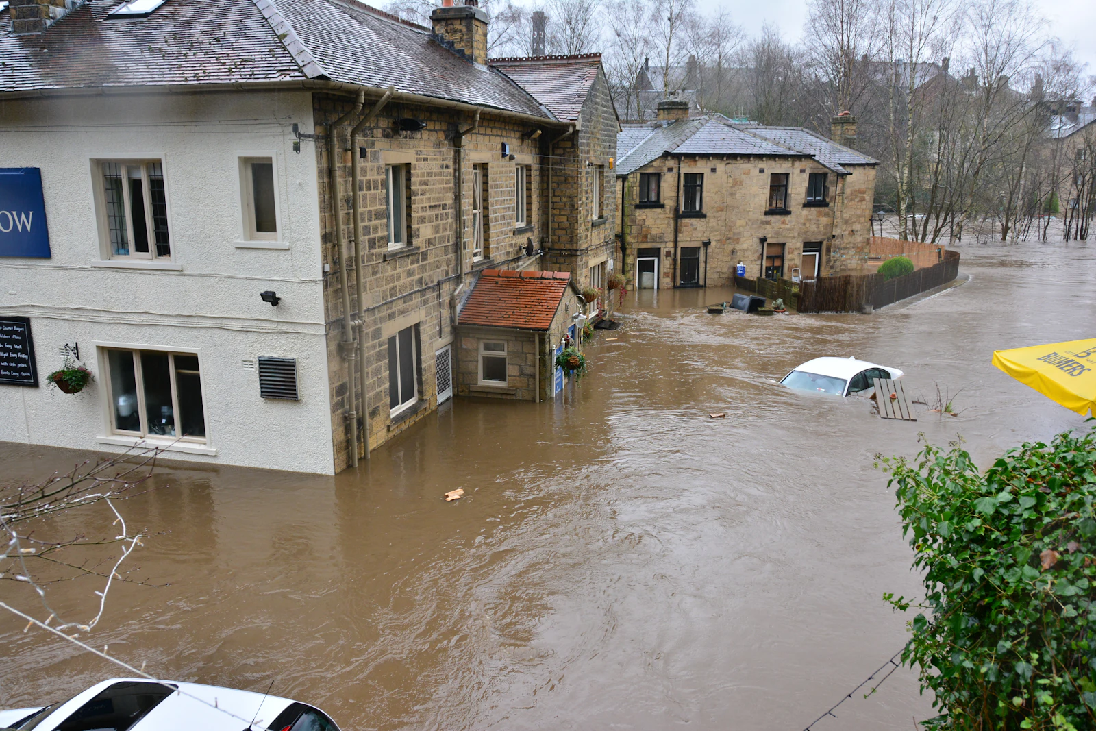 Floodwater surrounding stone buildings and a partly submerged car