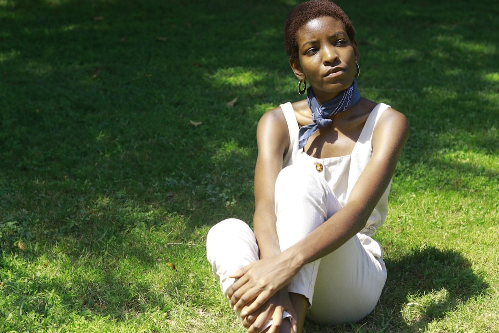 woman in white tank top sitting on green grass field