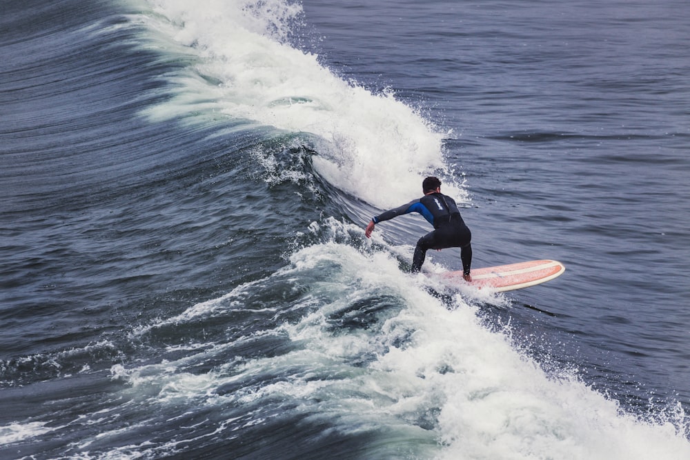 man in black wet suit surfing on sea waves during daytime