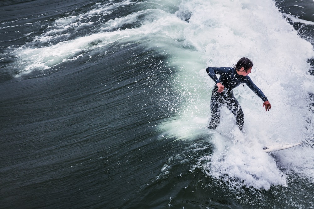 man in black wet suit surfing on sea waves during daytime