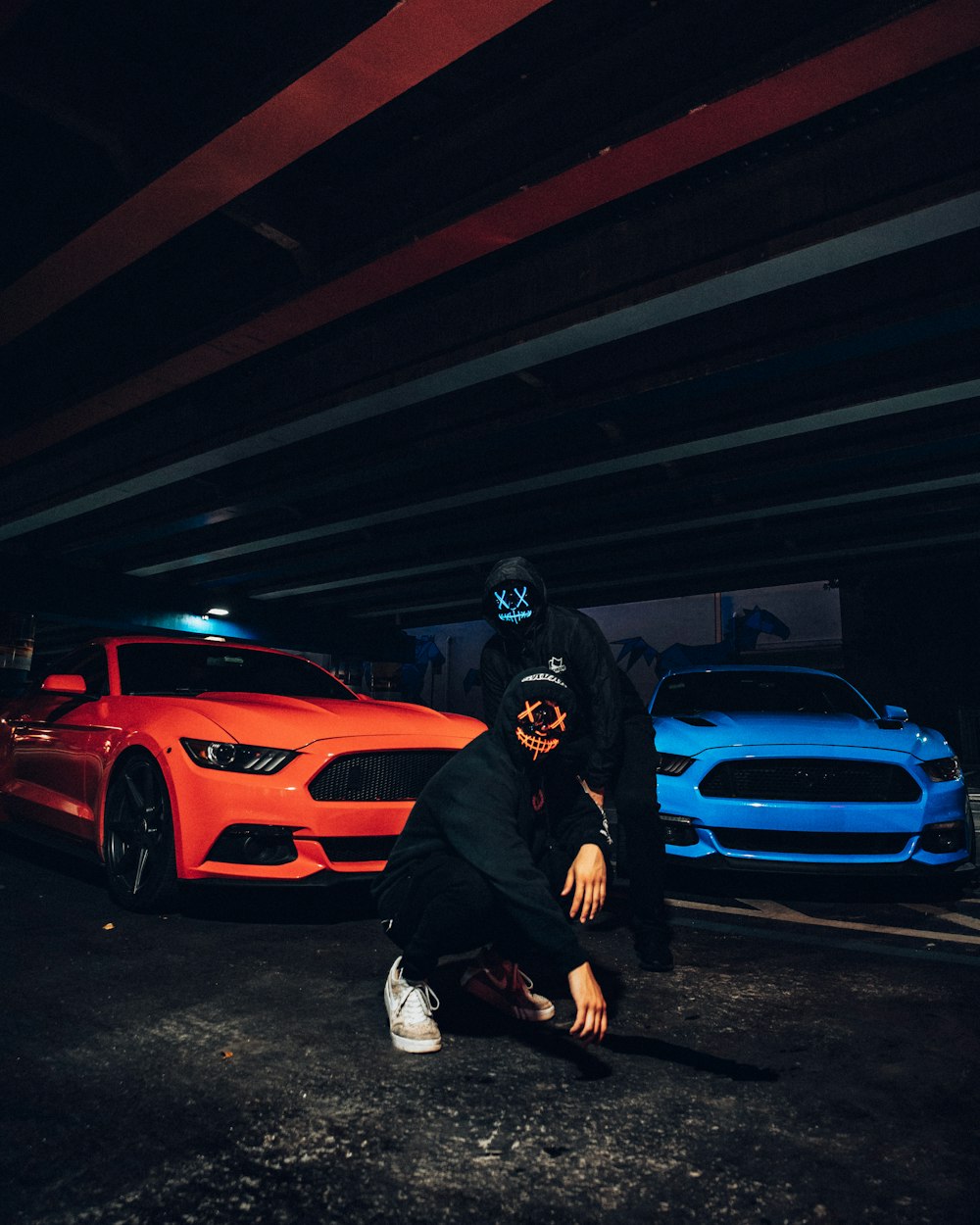 Hombre con chaqueta negra y casco negro de pie junto al coche rojo