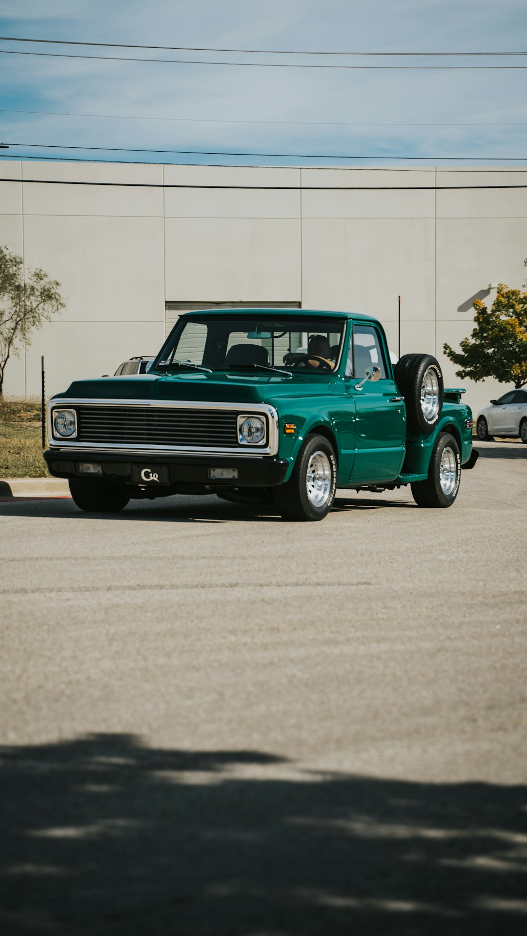 green chevrolet single cab pickup truck parked on gray concrete road during daytime