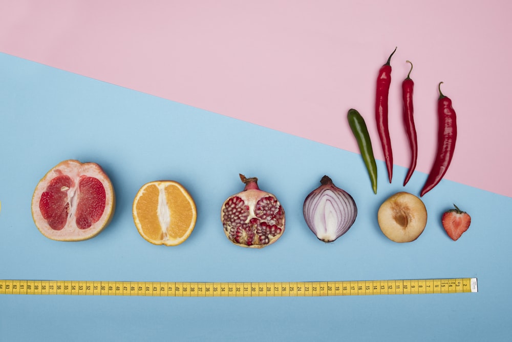 sliced orange fruit and orange fruit on pink surface