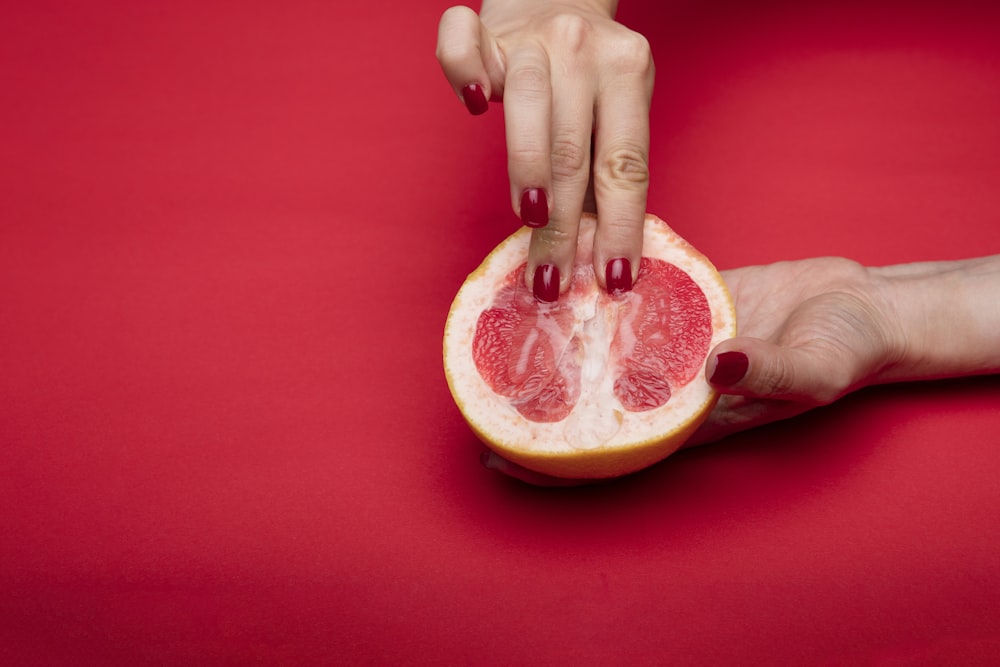 Person, die geschnittene Orangenfrüchte hält