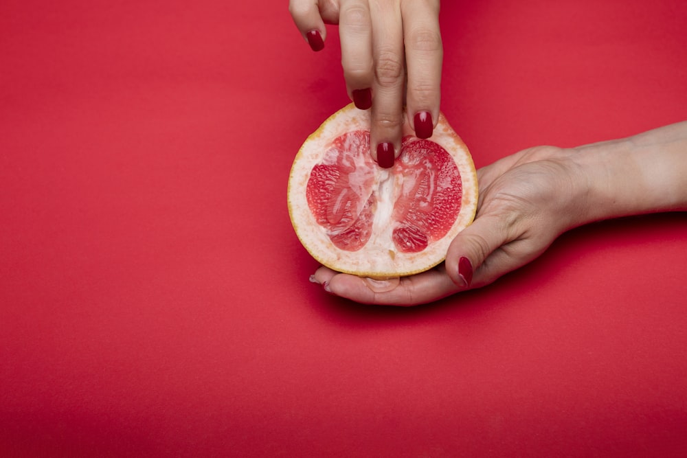 person holding sliced of orange fruit