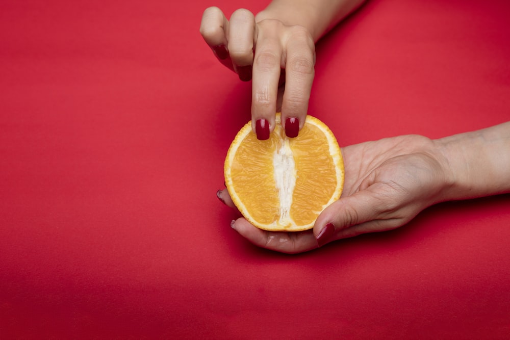 sliced orange fruit on persons hand