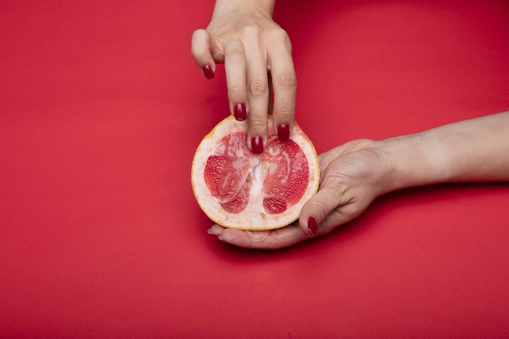 person holding sliced of orange fruit