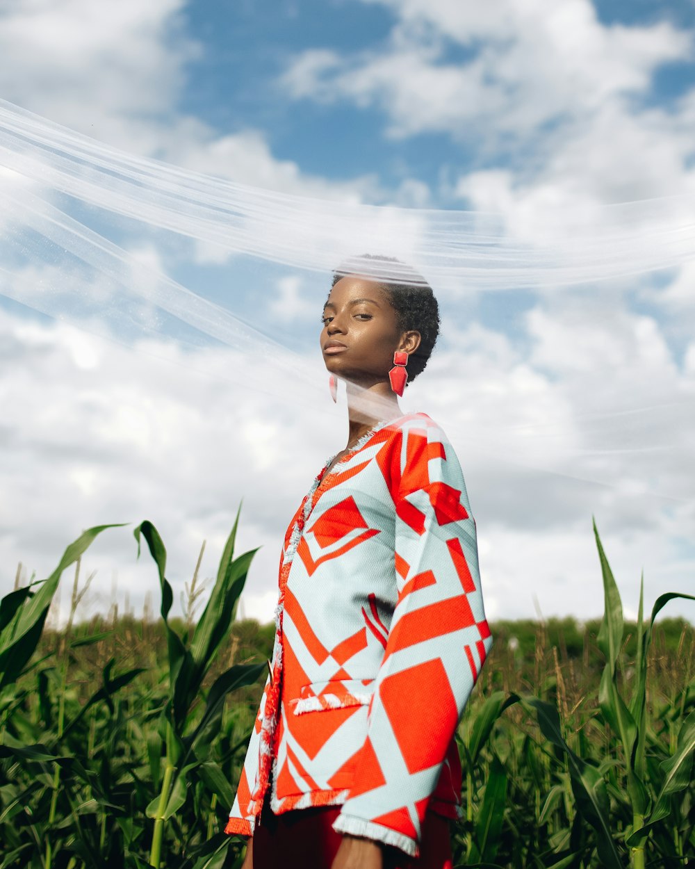 woman in white red and blue floral long sleeve shirt standing on green grass field under