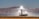 Three tall, industrial-looking solar power towers are located in a desert landscape with mountains in the background. The towers are brightly illuminated at the top, likely from concentrated sunlight. Surrounding the towers are arrays of mirrors used to direct sunlight towards the towers.