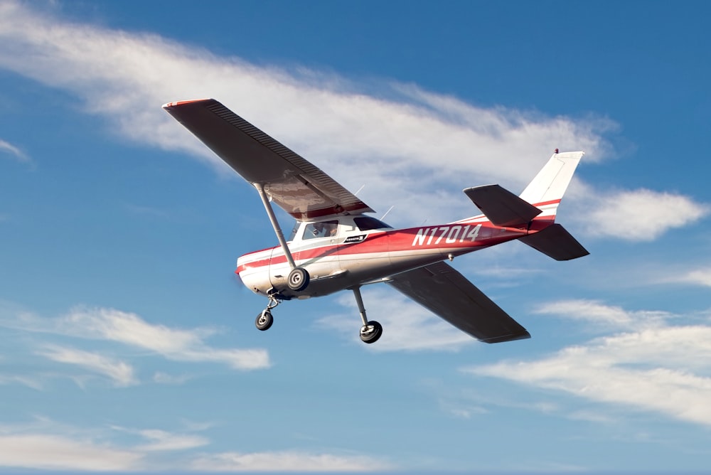 red and white airplane flying in the sky during daytime