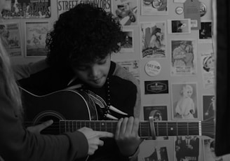 man playing guitar in grayscale photography