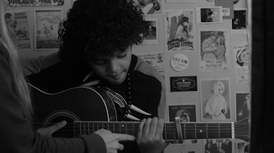 man playing guitar in grayscale photography