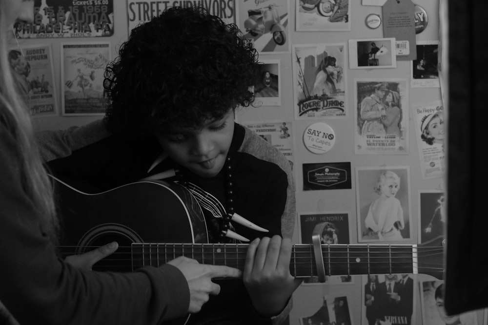 man playing guitar in grayscale photography