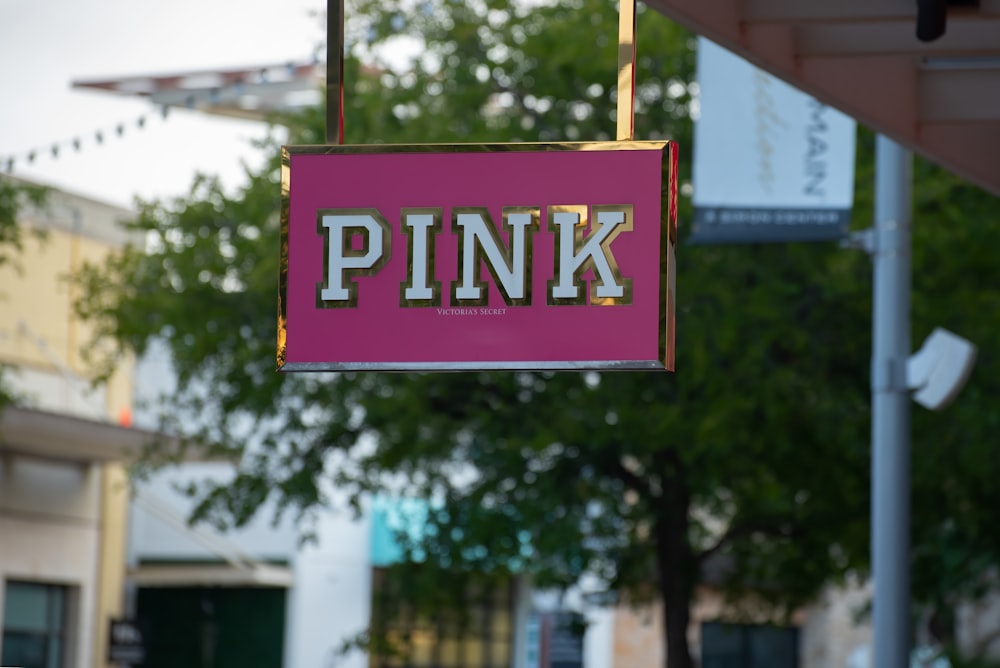 a pink sign hanging from the side of a building