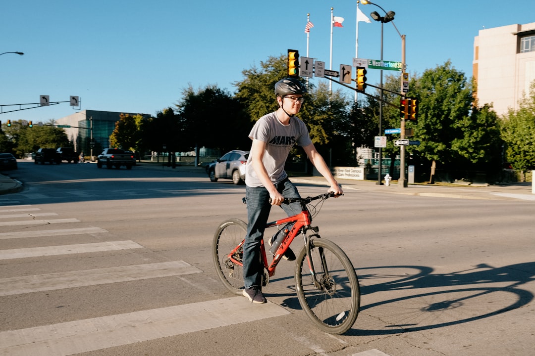 man in white t-shirt riding on red bicycle during daytime
