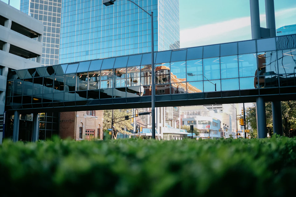 Large glass-facade building dominates cityscape with reflective surface and surrounding environment