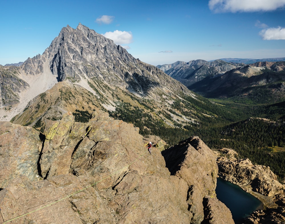 person in black jacket standing on rock formation near lake during daytime