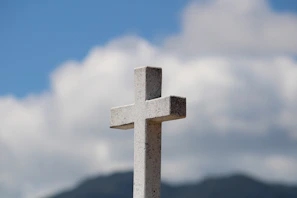 An ancient stone cross standing tall against a deep blue sky at dusk.