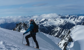 man in blue jacket and black pants riding ski blades on snow covered mountain during daytime