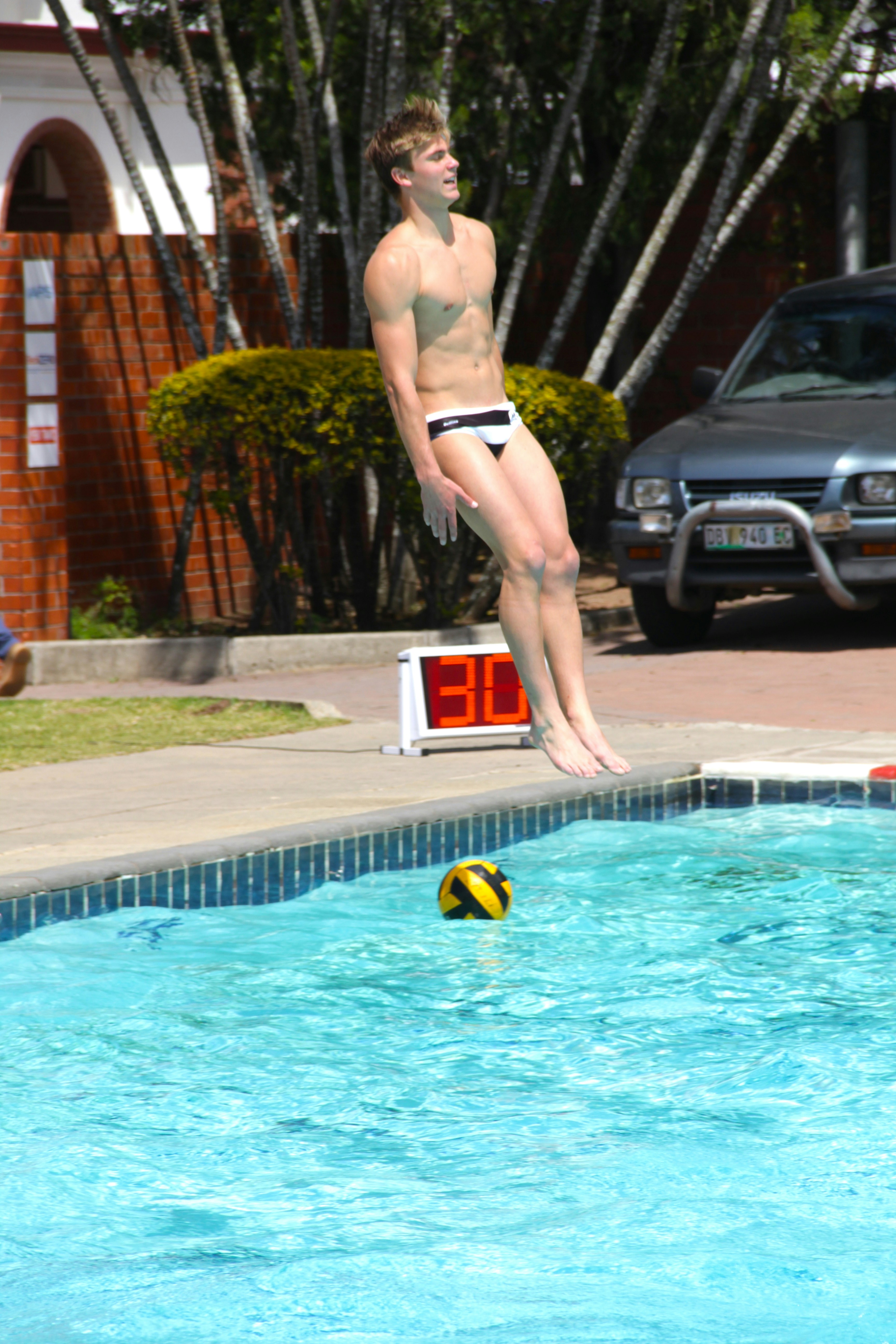 man in swimming trunks standing on swimming pool during daytime