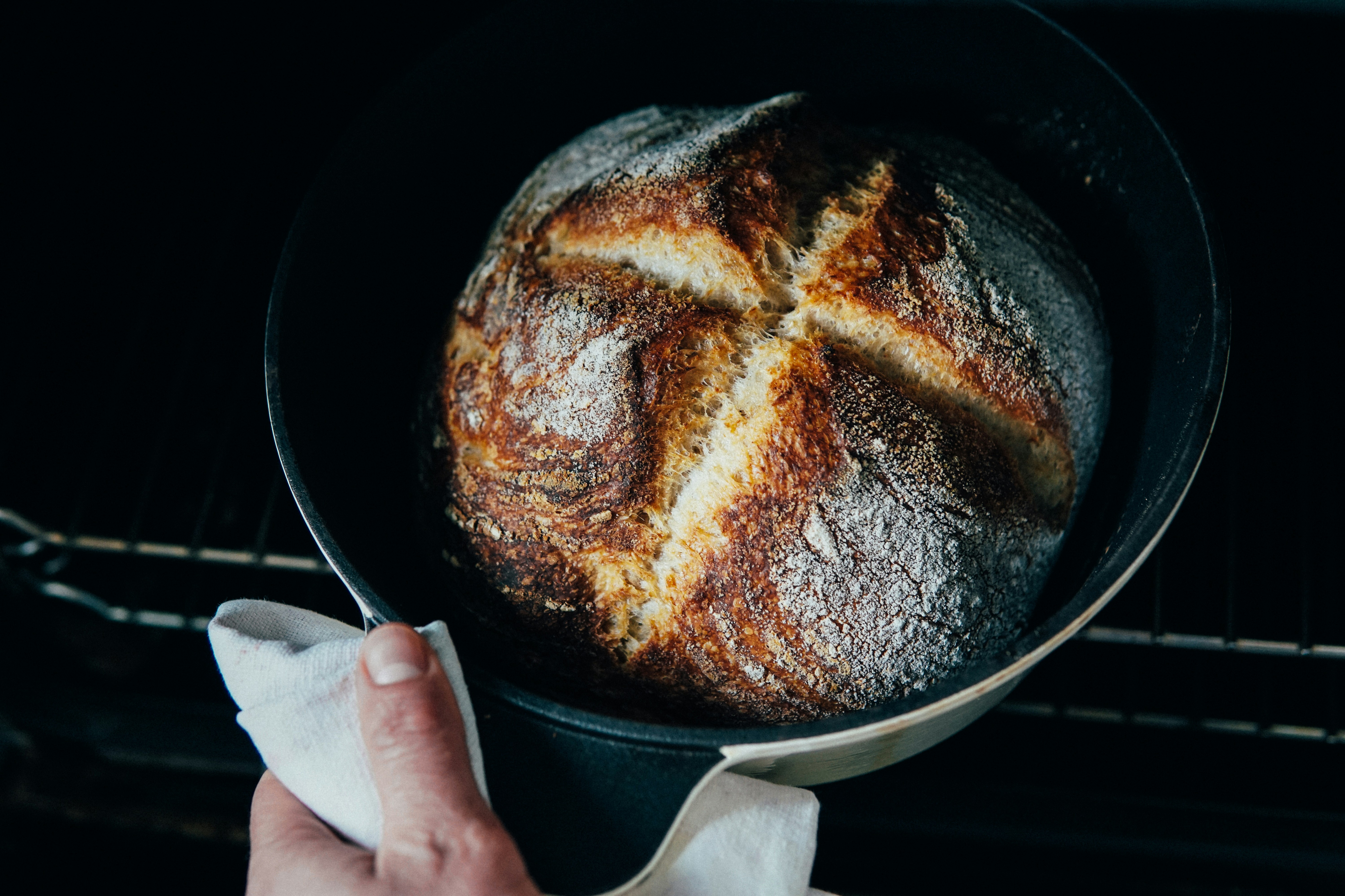 person-holding-a-black-round-tray-with-brown-bread