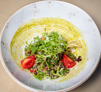 A close-up of a bright salad bowl filled with kale, cherry tomatoes, avocado, and quinoa.