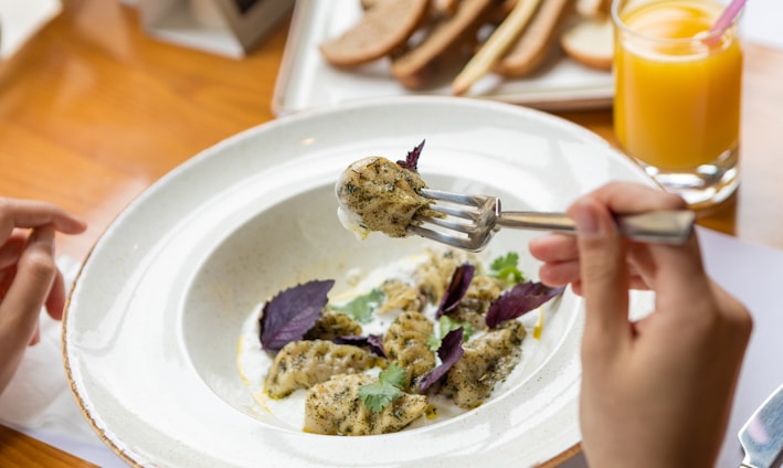 person holding stainless steel fork on white ceramic plate